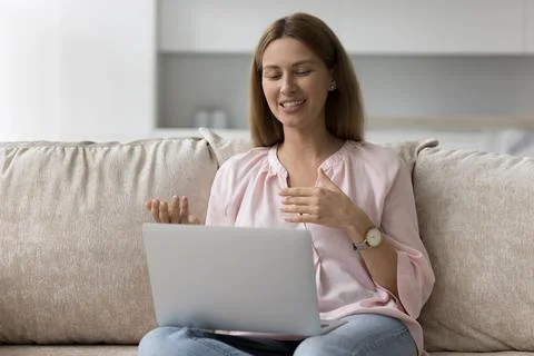 Woman talk through videoconference application sit on sofa with laptop Foto stock