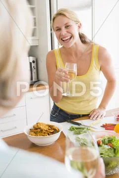 Woman talking to friend while preparing meal,mealtime Stock Photos