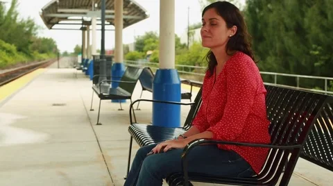 Woman talking on her cellphone while sitting at outdoor train station Stock Footage 56240557