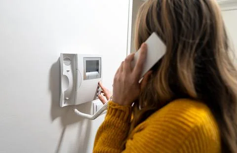 A woman is talking on the home intercom. Stock Photos
