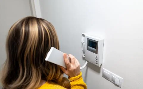 A woman is talking on the home intercom. Stock Photos