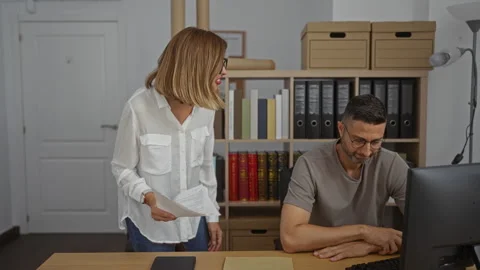 Woman talking to a man in an office setting with shelves, folders, and docu.. Stock Footage 296898345