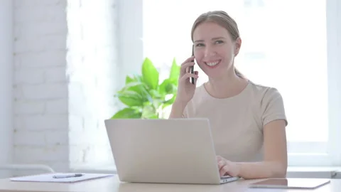 Woman Talking on Phone while using Laptop Stock Footage 205001204