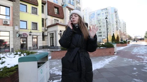 Woman talking on the phone while walking in a snowy city environment Stock Footage 297401351