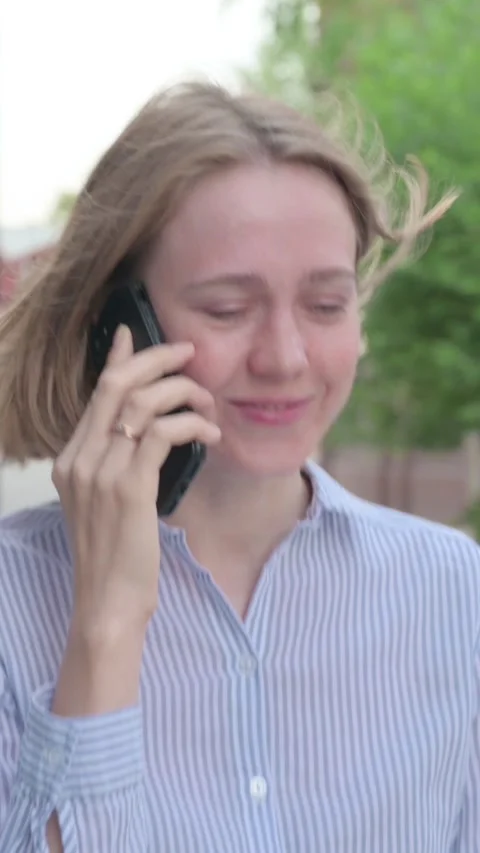 Woman Talking on Phone while Walking in Street, Vertical Video Stock Footage 339669432