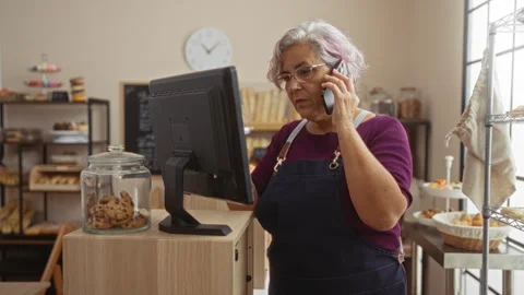 Woman talking on phone while working at cash register in bakery with cookie.. Stock Footage 298126159