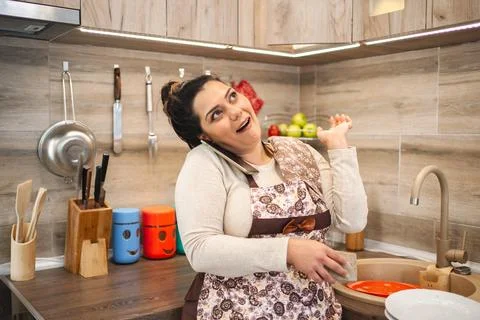 Woman talking on the phone while working in the kitchen Stock Photos