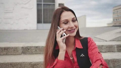 Woman talking on smart phone while sitting on the steps outdoors Stock Footage 80789138