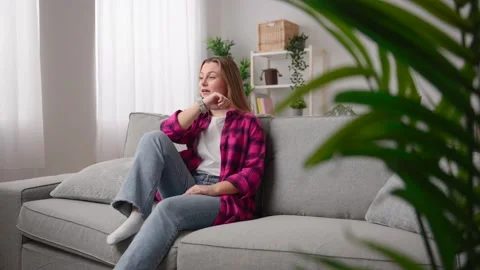 Woman talking on smart watch while sitting on couch Stock Footage 233464262