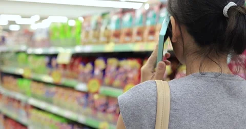 Woman talking on smartphone while shopping in a supermarket aisle Stock Footage 338192059