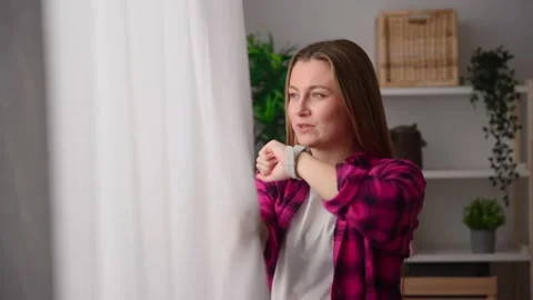 Woman talking on smartwatch while looking through the window Stock Footage 233464253