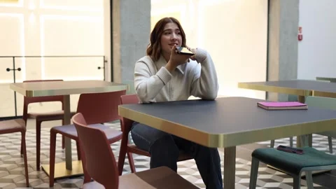 Woman talks to artificial intelligence on phone while sitting alone in cafe Stock Footage 323738751