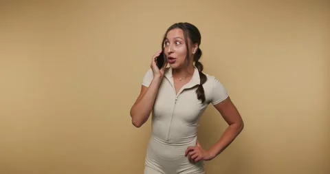 Woman talks on phone while changing expressions in a studio setting Stock-Footage 331990082