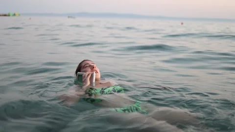 Woman talks on smartphone in sea using modern waterproof technology Stock Footage 344101676