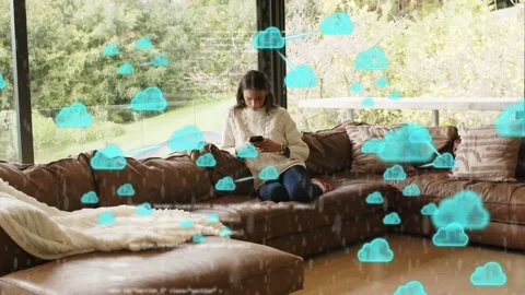 Woman tapping phone on sofa, causing cloud icons, code overlaying woman and Stock Footage 333369216
