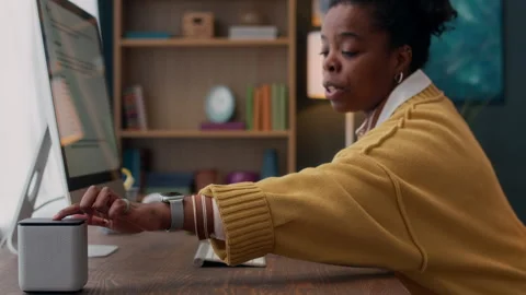 Woman Tapping on Smart Speaker while Working at Desktop Computer Stock Footage 307863609