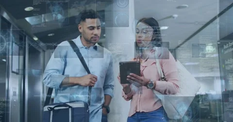 Woman tapping tablet and activating AR overlay over screen, man leaning in Stock Footage 321549906