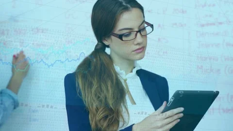 Woman tapping tablet and checking data with board as colleague drawing chart Stock Footage 335282566