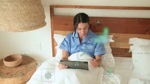 Woman tapping tablet on bed making AR tech graphs across screen monitoring CO2 Stock Footage 333004943