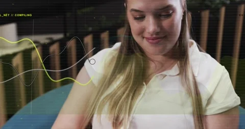 Woman tapping tablet on lap, starting COMPILING waveform for tech preview while Stock Footage 334307570