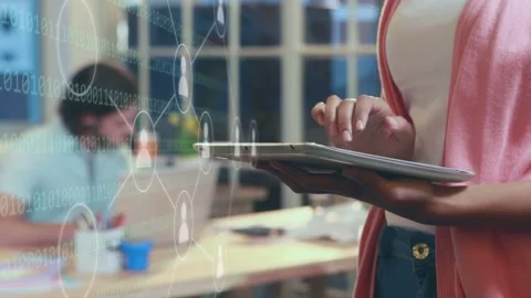 Woman tapping tablet in shared workspace, growing network icons and binary code Stock Footage 334789002