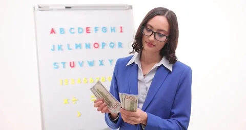 Woman teacher counts stack of dollar bills carefully Stock Footage 287251717