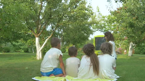 The woman teaches the children in the garden Stock Footage