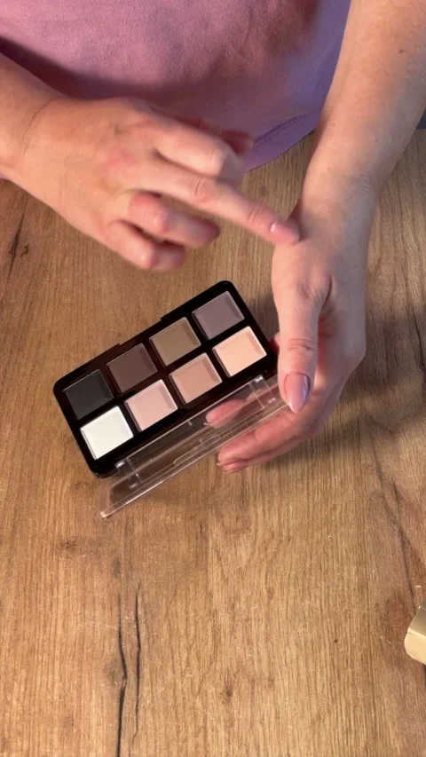 A woman is testing different shades from a makeup palette. Vertical video. 库存影片 302104593