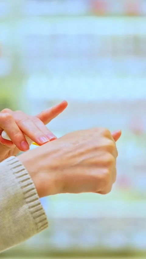 Woman testing serum texture on her hand before purchase in a beauty store Stock Footage 321899605