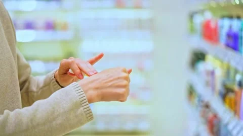 Woman testing serum texture on her hand before purchase in a beauty store Stock Footage 321899636