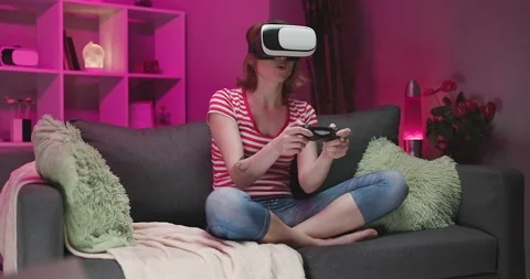 Woman testing virtual reality glasses while sitting on sofa in home interior Stock Footage 194464658