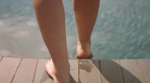 A woman testing the water in a pool with her toes, in slow motion Stock Footage 58891353