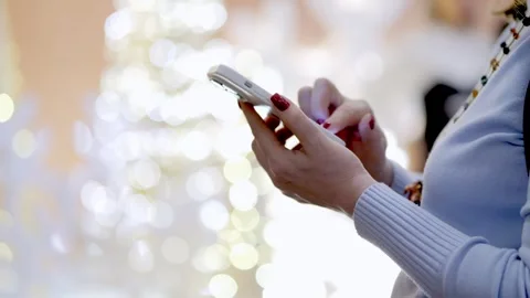 Woman is texting on her phone while standing in front of a Christmas tree Stock Footage 300931932