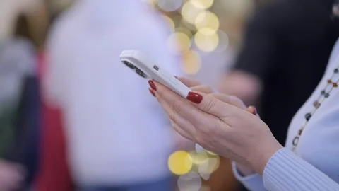 Woman is texting on her phone while standing in front of a Christmas tree Stock Footage 302260831