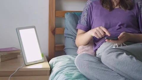 Woman texting on smartphone while relaxing by light therapy lamp in winter Stock Footage 222000749