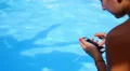 Woman Texting SMS on her Mobile Phone on the Beautiful Blue Poolside during HD Footage