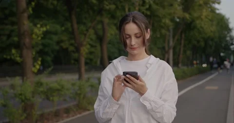 Woman texting while chatting on the smartphone and smiling on the street Stock Footage 201405978