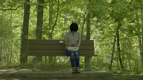 Woman texting while sitting on park bench. 4K UHD. Stock-Footage 50193364
