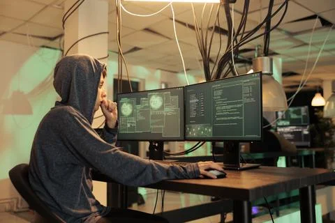 Woman thief trying to hack computer system at night Stock Photos