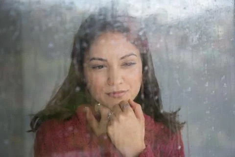 Woman, thinking about something while looking out the window on a rainy day. 写真素材