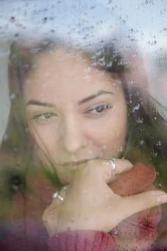 Woman, thinking about something while looking out the window on a rainy day. 写真素材