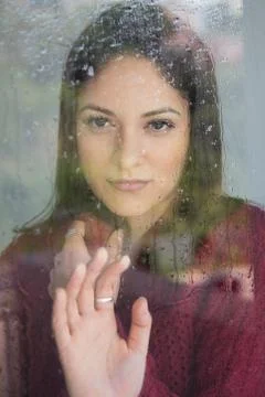 Woman, thinking about something while looking out the window on a rainy day. 写真素材