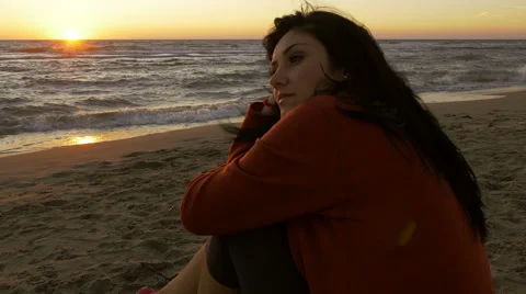 Woman thinking in front of ocean at sunset steadycam shot Stock Footage 64681232
