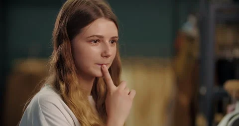 Woman thinking while choosing clothes in store Stock Footage 320646448