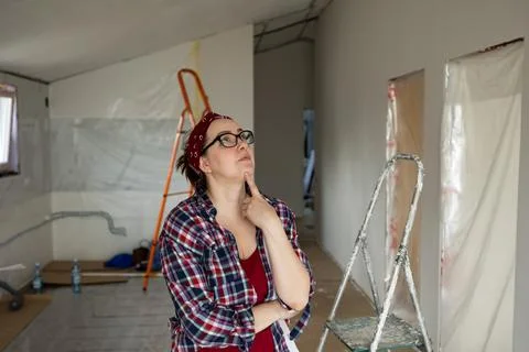 A woman thoughtfully examines the ceiling while appraising the painting job. Stock Photos