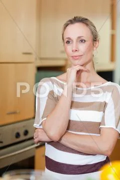 Woman in thoughts standing in kitchen Stock Photos