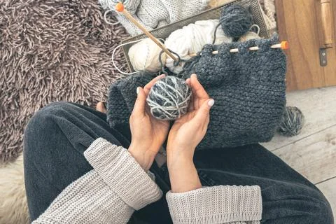 A woman with threads knits while sitting on the floor at home, top view. Foto stock