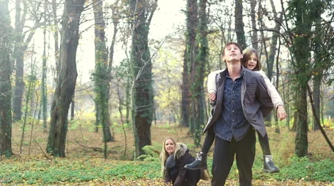 Woman throwing leaves at her daughter and husband in the park Stock Footage 59553944