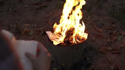 A woman throws paper documents into the fire, destruction of evidence 動画素材 142741634