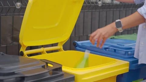 Woman throws plastic bottle into yellow recycling bin Stock Footage 340151196